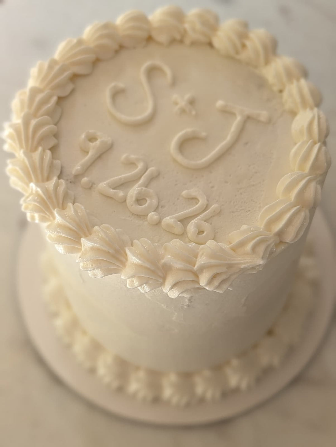 White buttercream mini cake with a piped border from Happy Hippo Bakery in Hutto, Texas