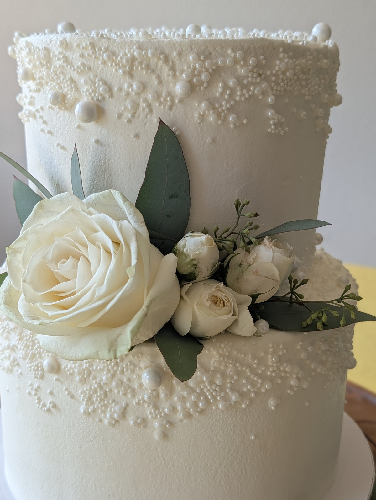 White pearl wedding cake with fresh white roses by Happy Hippo Bakery in Hutto, Texas